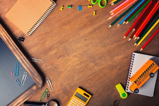 Notebook with school supplies on a wooden background