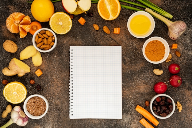 Notebook with a white screen around healthy foods to enhance immunity. Top view, copy space.