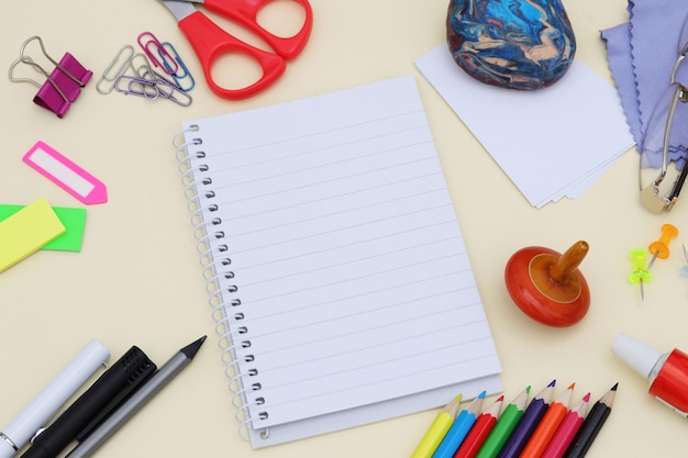 A notebook with a white sheet of paper on it and a red scissors on the right side.