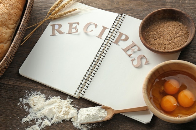 Photo notebook with word recipes and ingredients for making bread on table