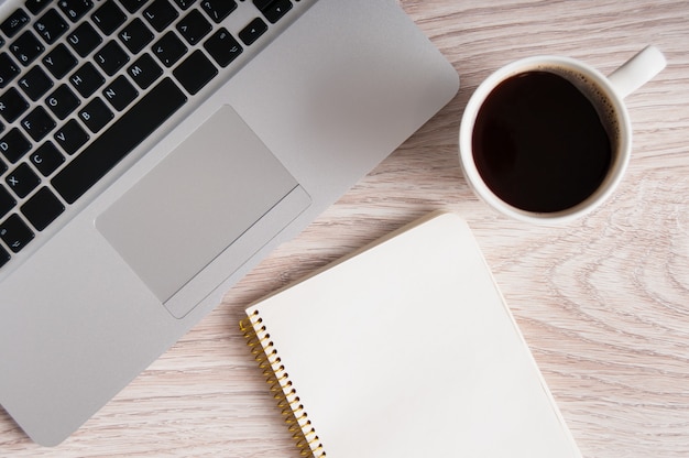 Notepad, laptop and coffee cup on wood table