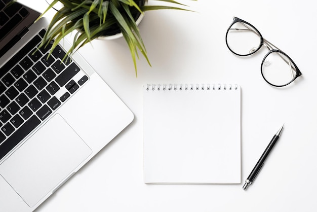 Notepad mockup on white background with laptop glasses house plant and pen Workplace with template