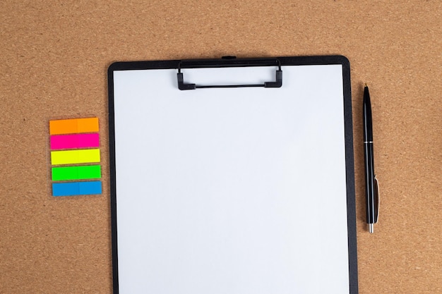 A notepad with a blank sheet of paper and a pen next to it on the table