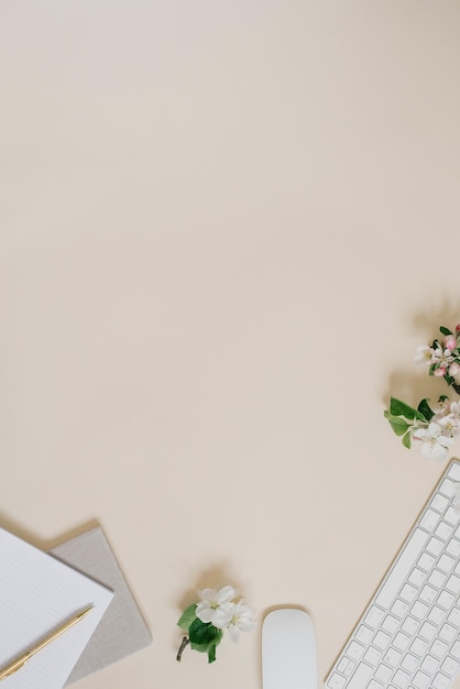 Notepad with a pen a branch with green leaves and white flowers and a laptop keyboard