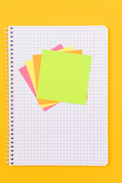 A notepad with sticky notes on yellow table