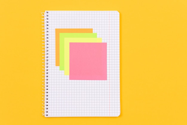 A notepad with sticky notes on yellow table