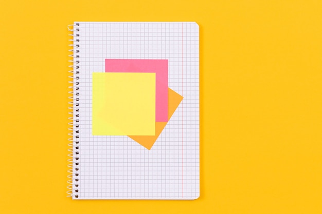 A notepad with sticky notes on yellow table