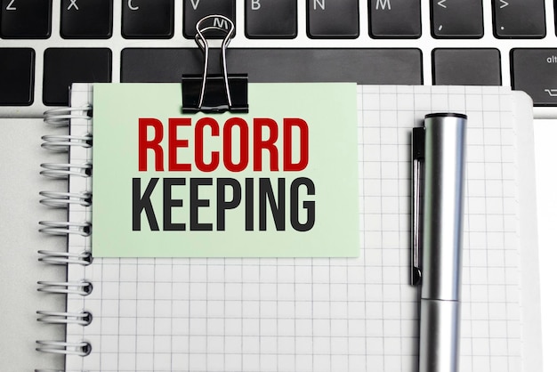 Notepad with the text on laptop RECORD KEEPING