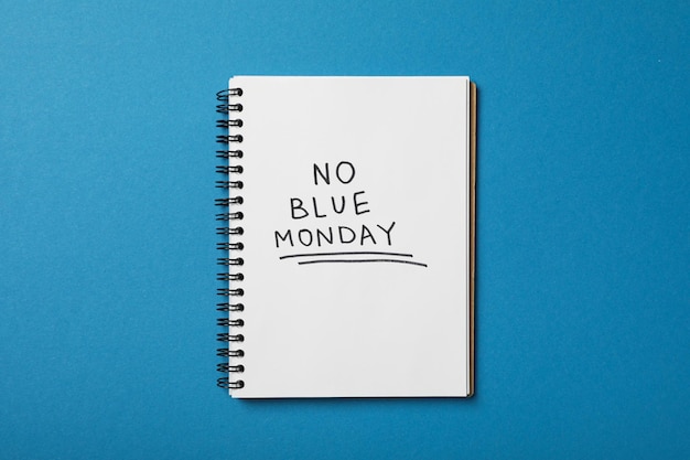 Notepad with text No Blue Monday on blue background top view