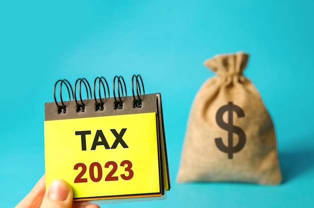 Notes with word Taxes 2023 and money bag The concept of paying the tax rate Taxation taxes burden Pay off debts Property income annual taxes