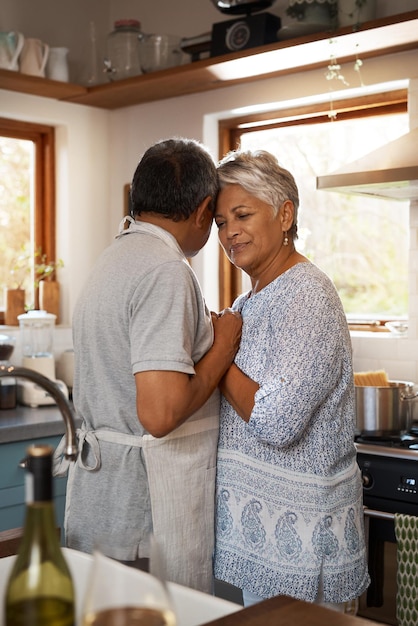 Nothing comes closer to the comfort of love Shot of a happy mature couple dancing together while cooking in the kitchen at home