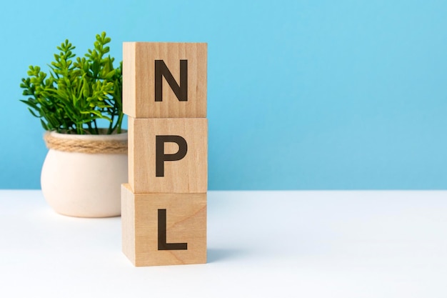 Npl word from wooden blocks with letters business concept on blue background copy space available npl short for non performing loans