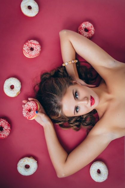 Nude woman lying with donuts around