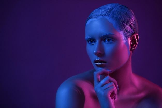 Nude Young Model with Creative Make Up on Dark Background in Blue Neon Light.