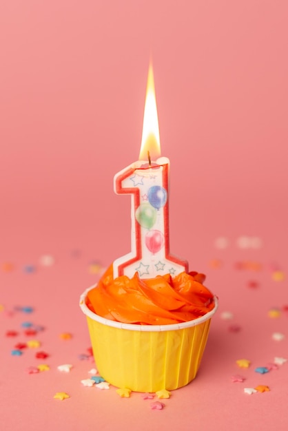 Number 1 candle in a cupcake against a pastel pink background First bithday cake