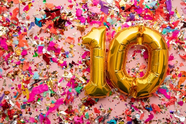 Number 10 gold birthday celebration balloon on a confetti glitter background