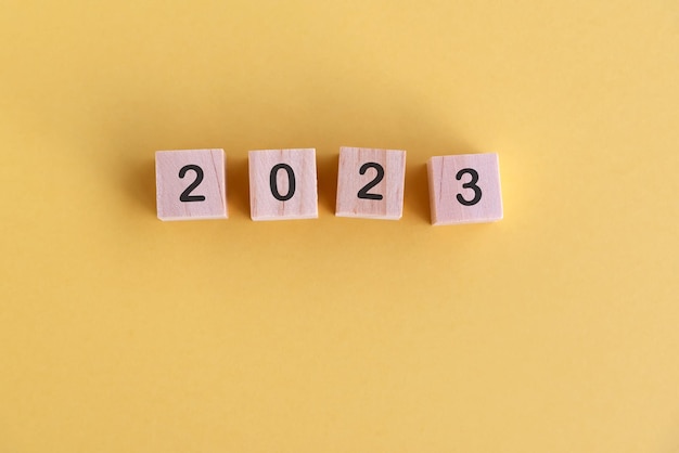 Number 2023 on wood block New Year concept yellow background