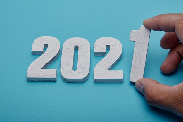 Photo numbers 2021 and hand on pastel blue background for new year