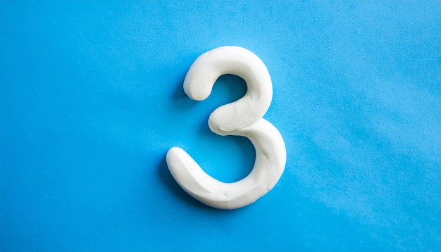 Photo numbers 3 made of white plasticine on blue background math learning development flat lay