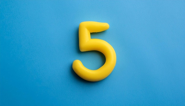 Numbers 5 made of yellow plasticine on blue background Math learning development Flat lay