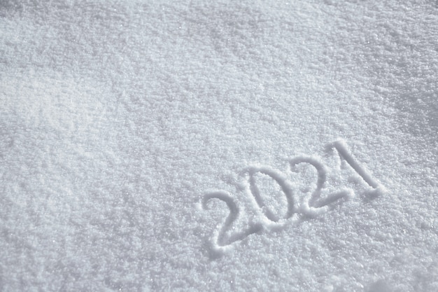 Numbers, calendar date, inscription 2021 on natural snowy surface in wintertime