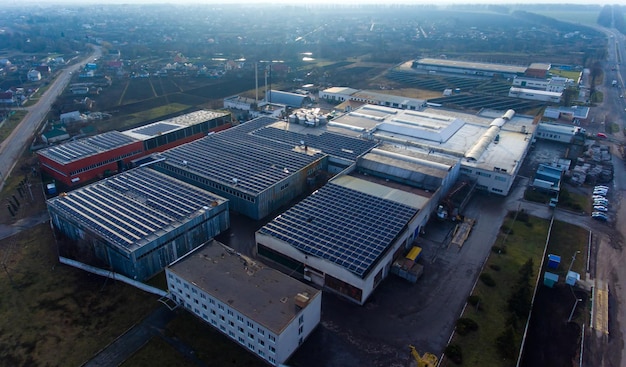 Numerous solar panels mounted on the industrial building Applying spacious roof area for producing clean energy View of the rural area at the background