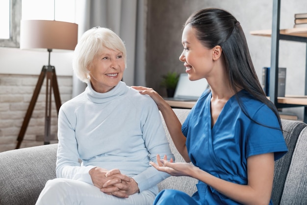 Nurse assisting with elderly woman at home