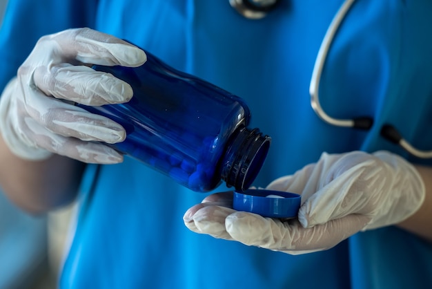 Nurse in blue uniform holding bottle with white pills. medical concept