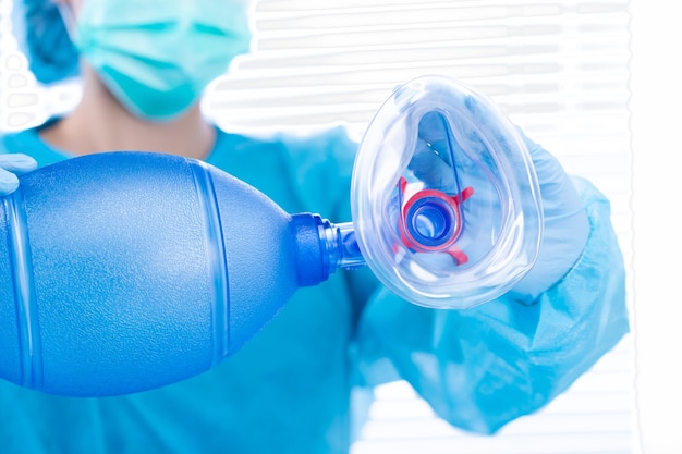 Nurse Doctor hold Oxygen Mask manual pump to camera Surgeon medical doctor put oxygen mask to patient respiratory breathing before surgical operation with blue uniform copy space