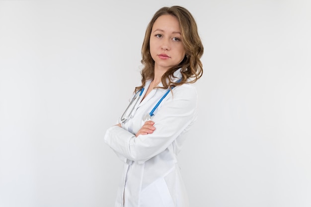 A nurse girl in a medical gown with a stethoscope around her neck and hands crossed on her stomach