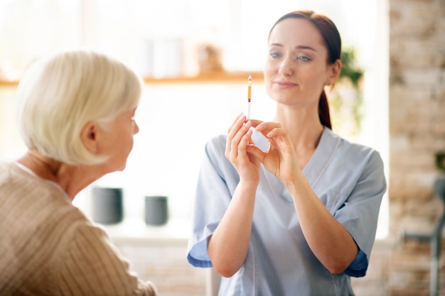 Nurse holding syringe before making injection for pensioner