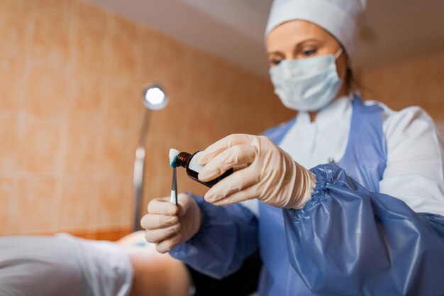 Nurse holds in hands tweezers and drips an antibacterial solution on cotton wool of brilliant green alcohol on cotton wool. Used in inflammatory skin diseases. Close-up