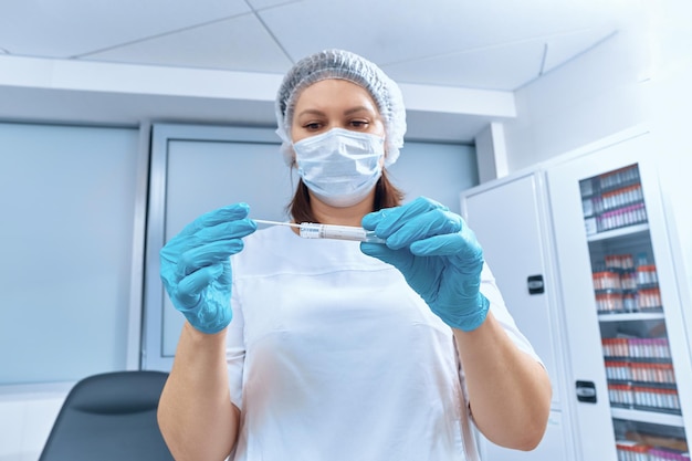 A nurse holds a test tube with a stick for a PCR test