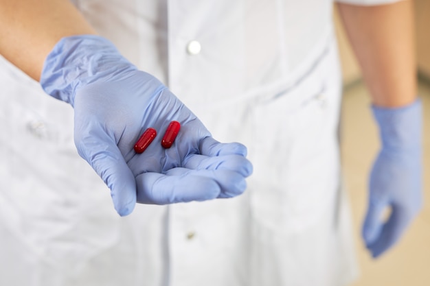 Photo nurse holds two red pills in her palm as a cure for the virus