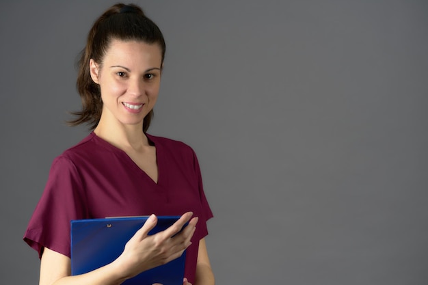 Nurse in purple uniform looking into camera with medical report