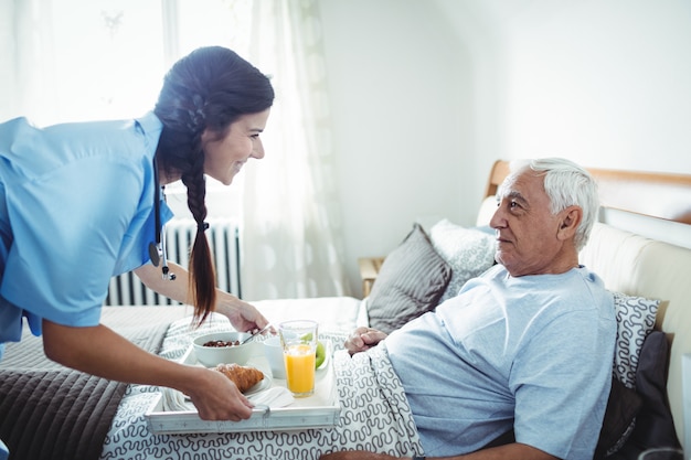 Nurse serving breakfast to senior man