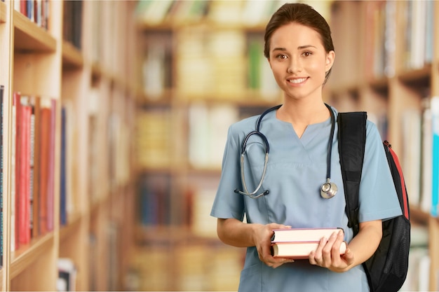 Nurse student with books and stethoscope in library