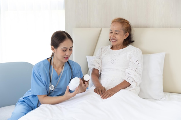 Nurse take care patient elderly senior asian woman present drug use to patients recovery on bed at home