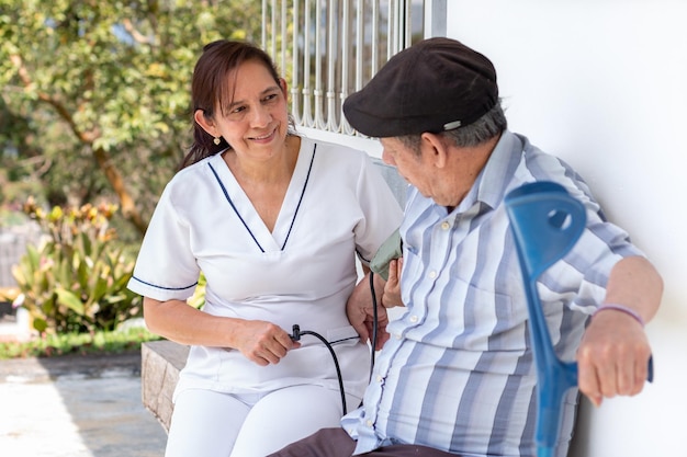 A nurse takes a disabled elderly man's blood pressure with a digital sphygmomanometer