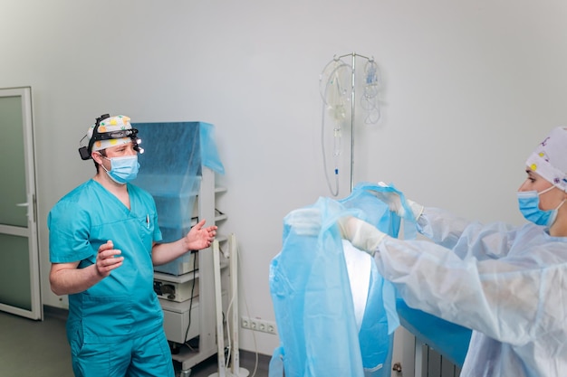 Nurse ties a sterile gown to the surgeon before the operation Doctors prepare for surgery in the operating room put on a medical uniform