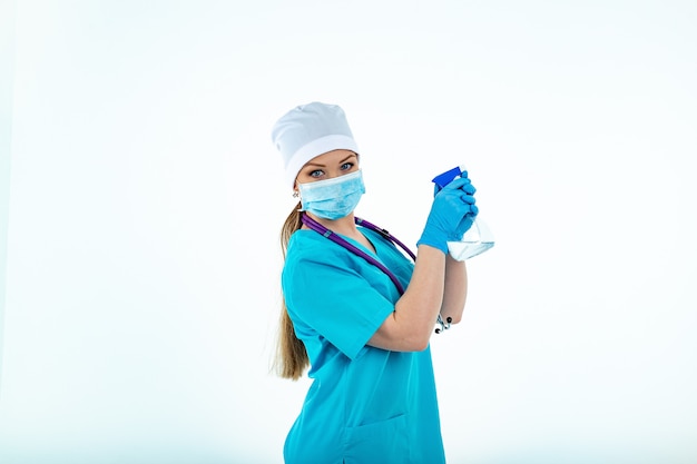 nurse in uniform in a medical mask and medical gloves holding in her hands a disinfectant spray