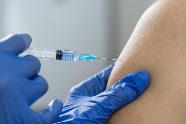 A nurse vaccinates a patient in the shoulder close-up. Mandatory vaccination during a dangerous flu epidemic.