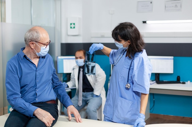 Nurse with face mask holding x ray scan for elder patient