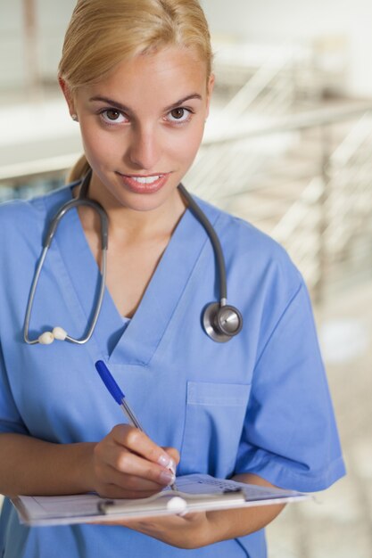 Nurse writing on a clipboard while looking at camera