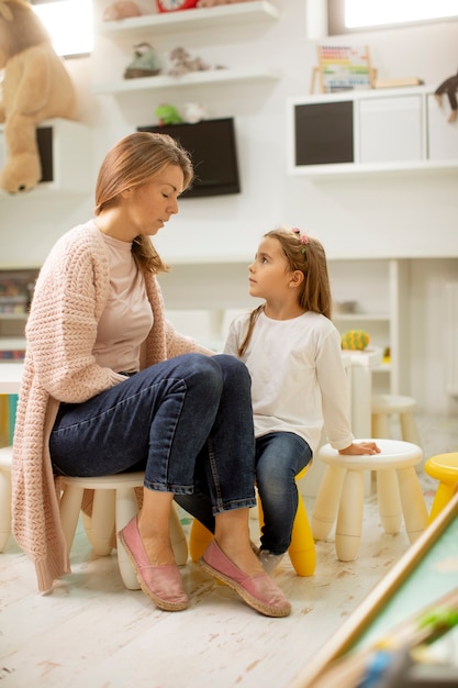 Nursery teacher talking to cute little girl with a problem in the kindergarten