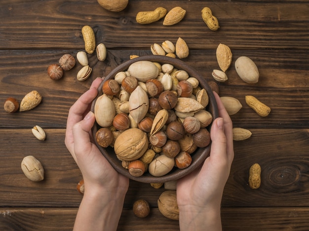 Nut mixture in a deep bowl in the hands of a woman over the table