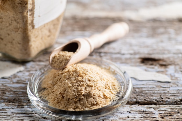 Nutritional yeast in flakes in a plate on wood background