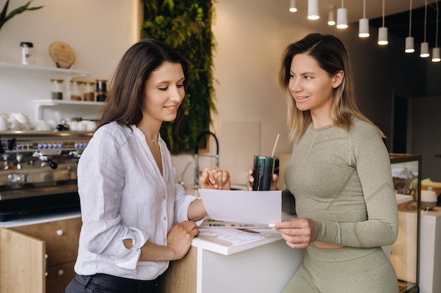 A nutritionist and a girl after fitness classes discuss healthy eating standing in a cafe