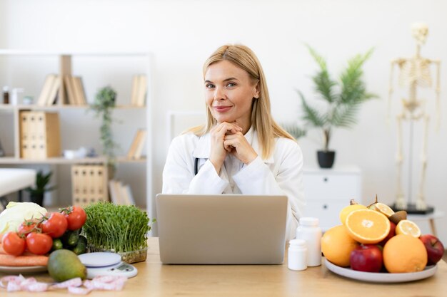 Photo nutritionist working on laptop and writing diet plan for patient