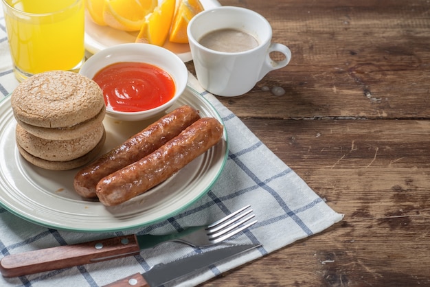 Nutritious breakfast, biscuits, strawberries, coffee, sausages, orange juice on the table